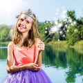 Cute girl playing with magic wand at lake. Royalty Free Stock Photo