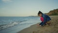 Cute girl playing sand on sea beach. Kid enjoying holiday at nature shoreline. Royalty Free Stock Photo