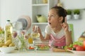 Cute girl preparing delicious fresh salad in kitchen