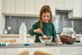 A cute girl prepearing her quick breakfast made of chocolate cereal balls and milk stirring with a spoon Royalty Free Stock Photo
