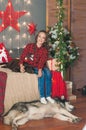 Cute girl in a red checkered shirt with dog labrador at home in the room decorated for Christmas. Royalty Free Stock Photo
