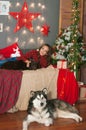 Cute girl in a red checkered shirt with dog labrador at home in the room decorated for Christmas. Royalty Free Stock Photo