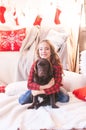 Cute girl in a red checkered shirt with dog labrador at home in the room decorated for Christmas. Royalty Free Stock Photo