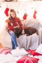 Cute girl in a red checkered shirt with dog labrador at home in the room decorated for Christmas. Royalty Free Stock Photo