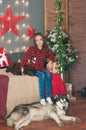 Cute girl in a red checkered shirt with dog labrador at home in the room decorated for Christmas. Royalty Free Stock Photo