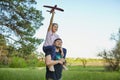 Cute girl riding on father`s shoulder and playing with toy airplane Royalty Free Stock Photo