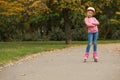 Cute girl roller skating in autumn park. Royalty Free Stock Photo