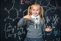 Cute girl in school uniform. Go to school for the first time. Girl indoors of the class room with blackboard on a background shows