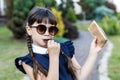 Cute girl, school years dressed in school uniform with pleasure eating black chocolate on the street in the park