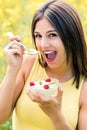 Cute girl showing yogurt bowl with fruit outdoors. Royalty Free Stock Photo