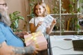 Cute girl shows card to daddy holding gift box at Fathers day celebration in room Royalty Free Stock Photo