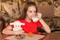 A girl sits at a table and enjoys drinking milk from a glass mug Royalty Free Stock Photo