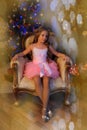 Cute girl sitting in a chair at the Christmas tree Royalty Free Stock Photo