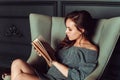 Cute girl sitting in a chair and reading a book in the office Royalty Free Stock Photo