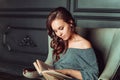 Cute girl sitting in a chair and reading a book in the office Royalty Free Stock Photo