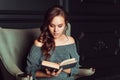 Cute girl sitting in a chair and reading a book in the office Royalty Free Stock Photo