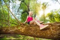 Cute girl sitting on fallen tree trunk in forest Royalty Free Stock Photo