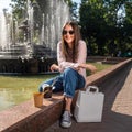 cute girl sitting by the fountain in nature, takeaway food, takeaway paper box mockup. Royalty Free Stock Photo