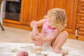 Cute girl sitting on the kitchen floor soiled with flour, playing with food, making mess and ha Royalty Free Stock Photo