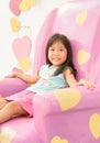 Cute girl sitting relax on pink sofa. Royalty Free Stock Photo