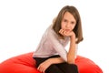 Cute girl sitting on round shape red beanbag chair Royalty Free Stock Photo