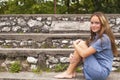 Cute girl sitting on the stone steps in the historic park. Royalty Free Stock Photo