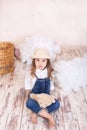 Cute girl sitting in the studio on the background of a balloon, stars and clouds and holding a teddy bear. The little girl is drea Royalty Free Stock Photo