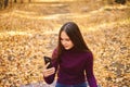 Cute girl with a smartphone in the autumn forest.