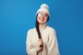 Cute girl smiles at camera, wears white hat and knitted white oversized sweater