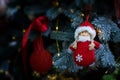 Cute girl snowman handmade hanging on a branch of a Christmas tree, background copy space. Red knitted clothes and fur trim.