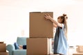 Cute girl stacking cardboard boxes indoors. Moving into new house