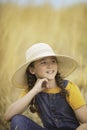 Cute girl in a straw hat, sitting in a field of hay in Eagle Mountain, Ut.