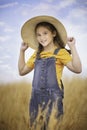 Cute girl in a straw hat, sitting in a field of hay in Eagle Mountain, Ut.