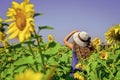 Cute girl in straw hat walking sunflowers farm, summer holidays