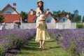 A cute little girl in straw hat and yellow dress runs to her beautiful mother in summer dress at home lavender garden.