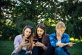 Cute girl students spend free time sitting on green grass in the park on summer day. One woman is reading a book Royalty Free Stock Photo