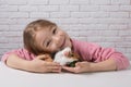 Cute girl at the table with her pet, feeding a guinea pig Royalty Free Stock Photo