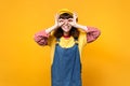 Cute girl teenager in french beret, denim sundress holding hands near eyes imitating glasses or binoculars isolated on Royalty Free Stock Photo