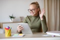 Cute girl teenager waving at digital tablet screen