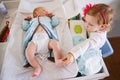 Cute girl toddler helping her mother, changing baby diaper Royalty Free Stock Photo