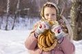 Cute girl in a traditional Russian headscarf with pancake and bagels on winter background. Royalty Free Stock Photo