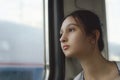 A cute girl travels by train and looks out the window.