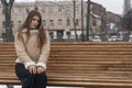 Cute girl in trendy beige sheepskin coat in winter outside. Young woman in winter outerwear relaxes in park Royalty Free Stock Photo