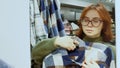 Girl tries on shirt to her face in front of mirror in store