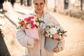 Cute girl with two lush flower bouquets with fresh roses, eustomas, alstroemerias and eucalyptus branches in gift boxes