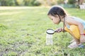 Cute girl using magnifying glass to look at bugs in glass jars Learn to use science-related observations Royalty Free Stock Photo