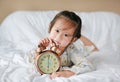 Cute little girl with alarm clock lying on bed Royalty Free Stock Photo