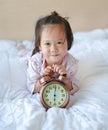 Cute little girl with alarm clock lying on bed Royalty Free Stock Photo