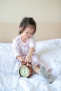 Cute little girl with alarm clock lying on bed Royalty Free Stock Photo