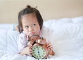 Cute little girl with alarm clock lying on bed Royalty Free Stock Photo